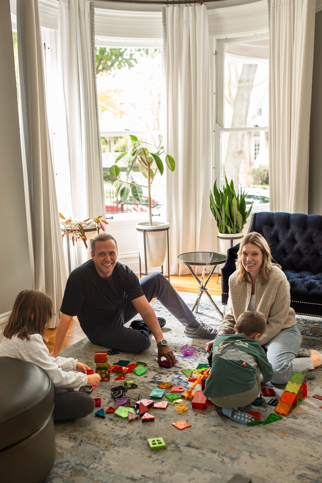 Dom and Shannon on the living room floor building with magnetic tiles alongside their kids