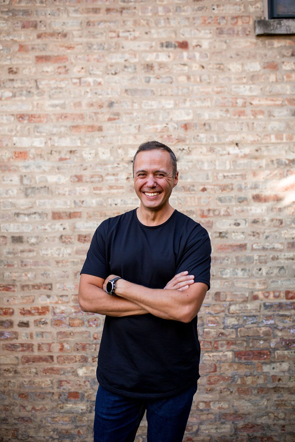 Dom smiling against a brick wall