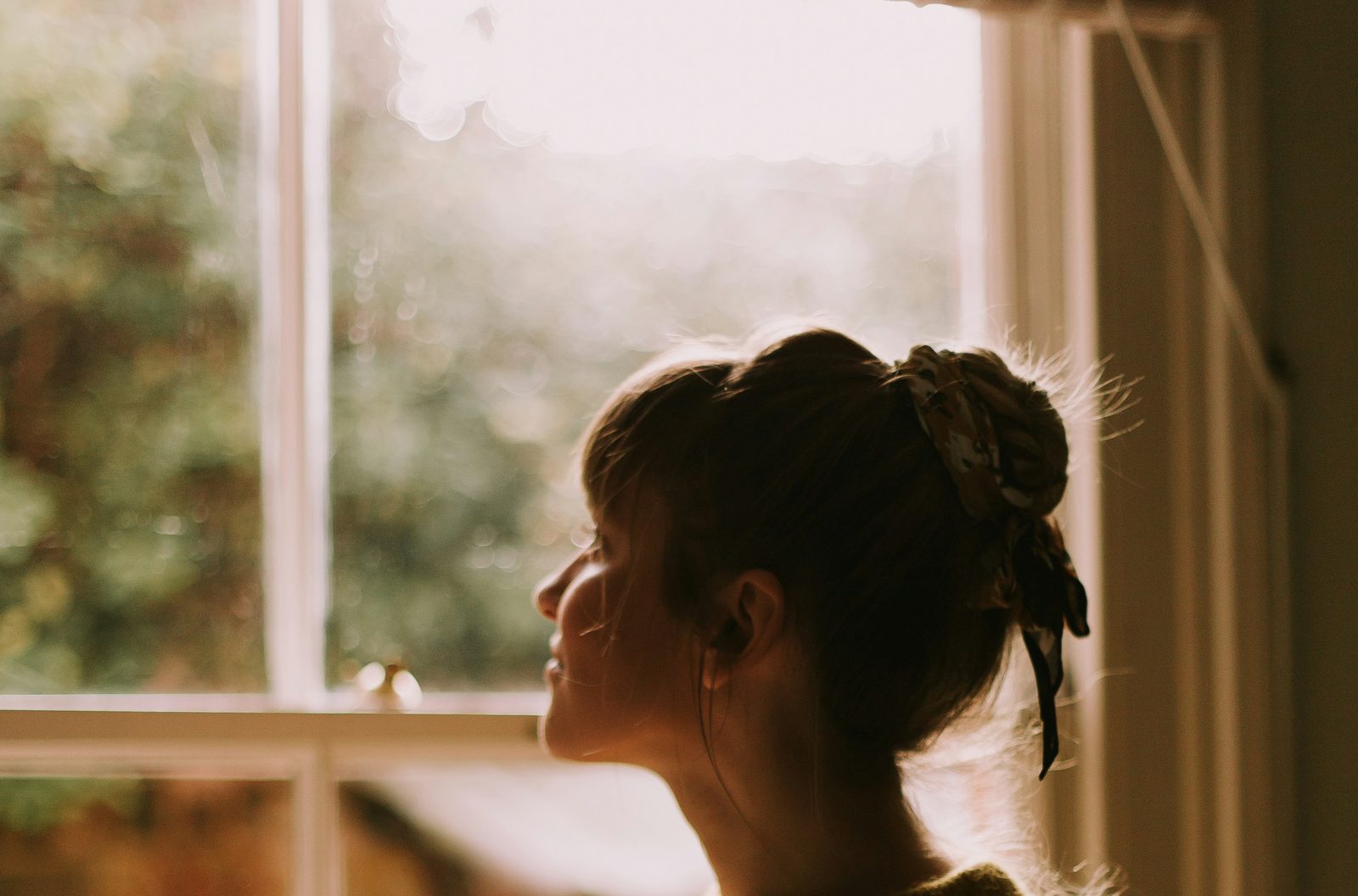 Parent with morning coffee in warm window light, back to herself