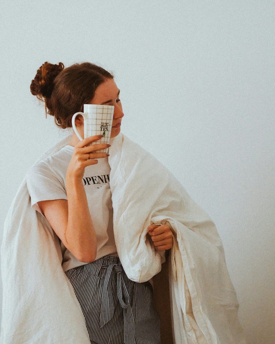 Parent wrapped in a duvet, coffee in hand, running on empty